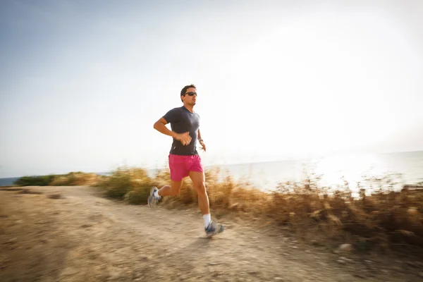 Caucásico joven corriendo en un camino de costa en un verano encantador —  Fotos de Stock