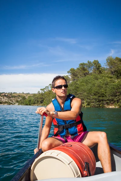 Handsome young man on a canoe on a lake, paddling, enjoying a lo — Stock Photo, Image