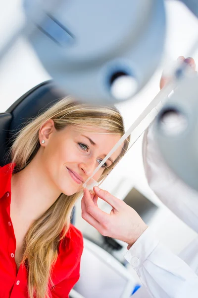 Concepto de optometría: mujer joven y bonita que examina sus ojos — Foto de Stock