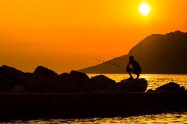 Fisherman's siluet renkli gün batımında sahilde