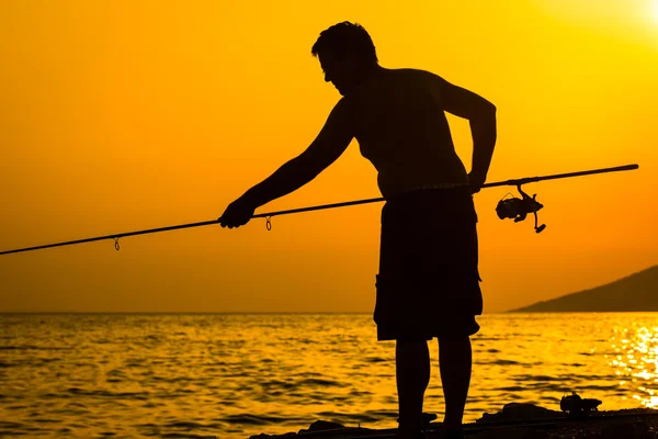 Fishermans siluett på stranden vid färgglada sunset — Stockfoto