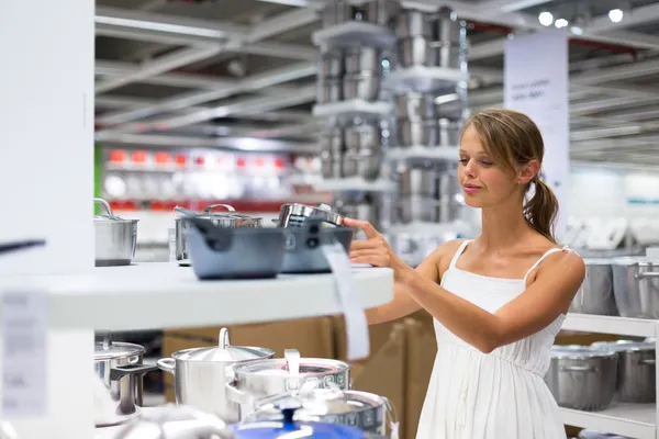 Mujer joven y bonita eligiendo la olla adecuada para su cocina — Foto de Stock