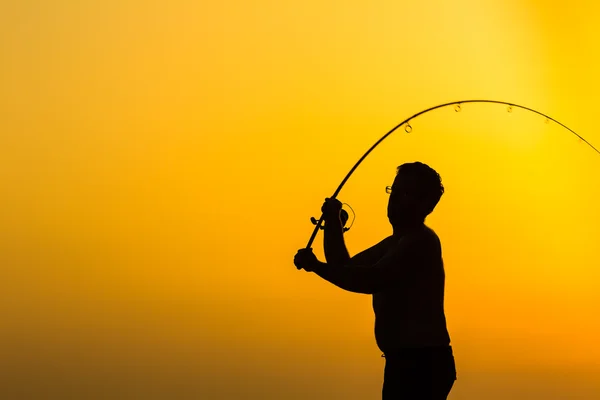 Silhueta de pescador na praia ao pôr-do-sol colorido — Fotografia de Stock