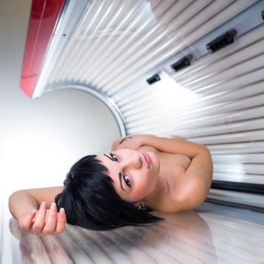 Pretty young woman tanning her skin in a modern solarium clipart