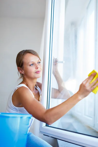 Csinos, fiatal nő házi munkát csinál - mosás ablakok — Stock Fotó