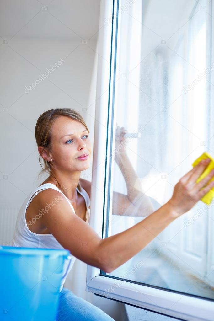 Pretty, young woman doing house work - washing windows