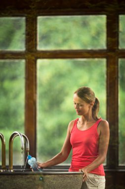 vrouw fillig een plastic fles met water