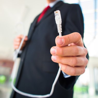 ethernet kablosu tutan işadamı