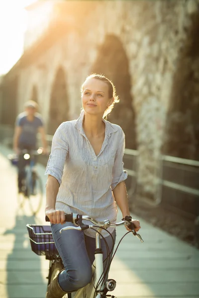 Kvinde ridning en cykel i en by - Stock-foto