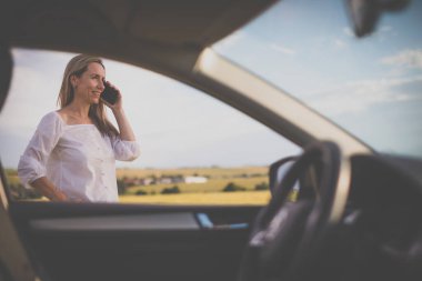 Arabasının direksiyonunda yaşlı, güzel bir kadın uzun bir yolculukta mola veriyor, bir telefon görüşmesi yapıyor.