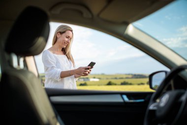 Arabasının direksiyonunda orta yaşlı güzel bir kadın uzun bir yolculukta mola veriyor, bir telefon görüşmesi yapıyor.
