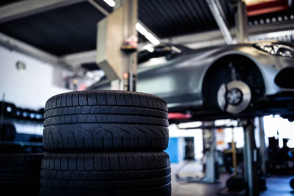 타이어의 균형을 맞추거나 수리하고 자동차 공장이나 작업장에서 정비공이 자동차 타이어를 — 스톡 사진