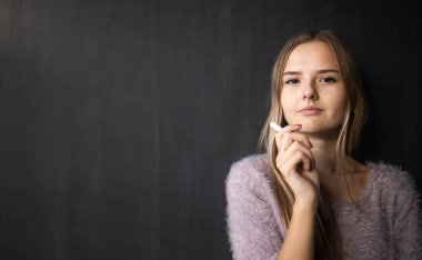 Güzel, genç bir kız öğrenci ders sırasında tahtası önünde.