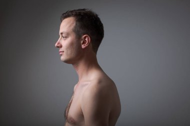 Gri arka planda yakışıklı bir gencin koyu renkli portresi.