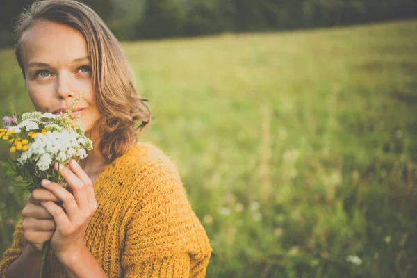 フィールド内の野生の花の花束を屋外で美しい若い女性は 自然を楽しんでいます 春の牧草地で幸せな女性 — ストック写真