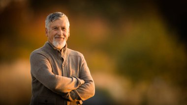 Sonbaharda açık havada yakışıklı bir son sınıf öğrencisinin portresi. Aktif son sınıf öğrencisi doğadaki emekliliğinin tadını çıkarıyor.