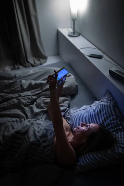 中世の女性は 夜にベッドで寝る前に彼女のタブレットコンピュータを使用して 睡眠の直前に青の光への暴露 — ストック写真