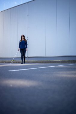 Görme engelli genç bir kadın, beyaz bastonuyla şehirde daha iyi geziniyor ve gideceği yere güvenli bir şekilde varıyor.