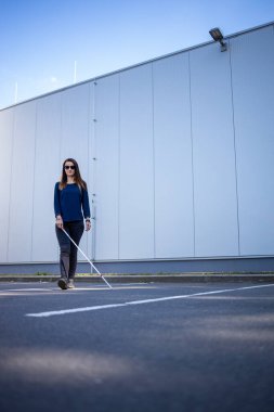 Görme engelli genç bir kadın, beyaz bastonuyla şehirde daha iyi geziniyor ve gideceği yere güvenli bir şekilde varıyor.