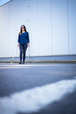 Görme engelli genç bir kadın, beyaz bastonuyla şehirde daha iyi geziniyor ve gideceği yere güvenli bir şekilde varıyor.