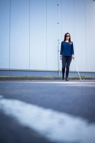 都市空間をよりよくナビゲートし 安全に彼女の目的地に到達するために彼女の白い杖を使用して 都市の通りを歩く視覚障害者の若い女性 — ストック写真