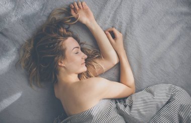 Güzel, genç bir kadın hafta sonu geç saatlere kadar yatağında uyuyor. Uykusuzluğunu telafi ediyor.