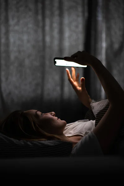 Jovem Mulher Cama Segurando Telefone Cansado Exausto Luz Azul Esticando — Fotografia de Stock