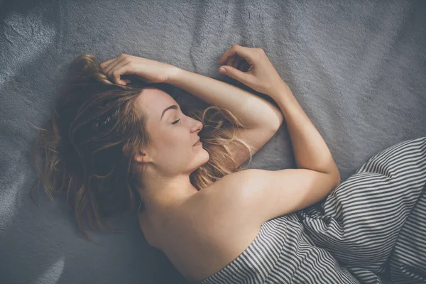 Güzel, genç bir kadın hafta sonu geç saatlere kadar yatağında uyuyor. Uykusuzluğunu telafi ediyor.