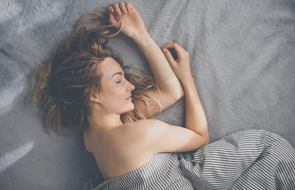 Güzel, genç bir kadın hafta sonu geç saatlere kadar yatağında uyuyor. Uykusuzluğunu telafi ediyor.
