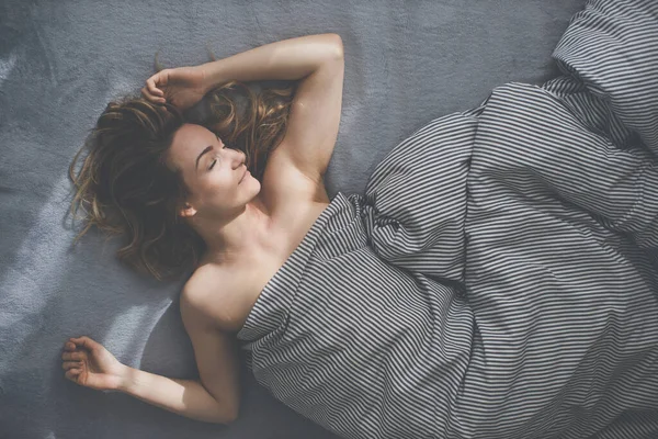 Güzel, genç bir kadın hafta sonu geç saatlere kadar yatağında uyuyor. Uykusuzluğunu telafi ediyor.