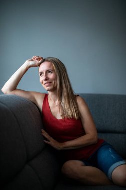 Evde oturan orta yaşlı kadın koltukta dinleniyor. (Renkli görüntü))