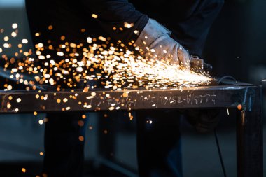 Öğütücüyle demir üzerinde çalışan adam. İş yerinde bir adam. Öğütücüden çıkan kıvılcımlar ve ateş. Öğütücü. İşçi.