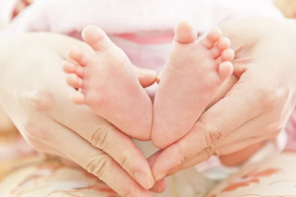 Voeten van pasgeboren baby in moeders handen — Stockfoto