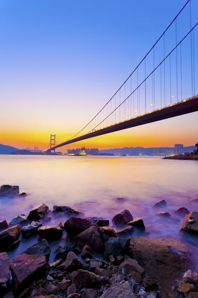 Bridge at coast with sea stones in sunset — Stock Photo, Image