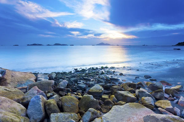 Coucher de soleil côte avec fond de pierres de mer — Photo