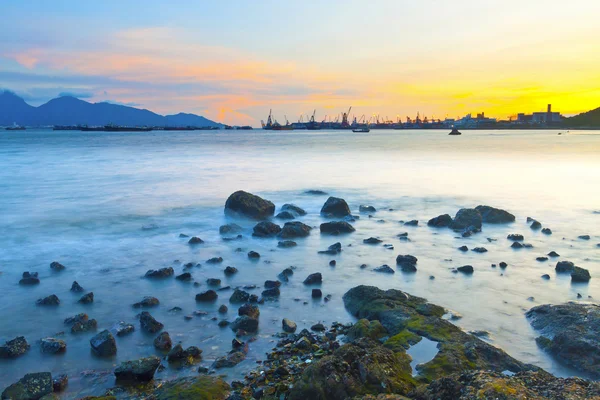 Pôr do sol ao longo da costa com pedras marinhas — Fotografia de Stock