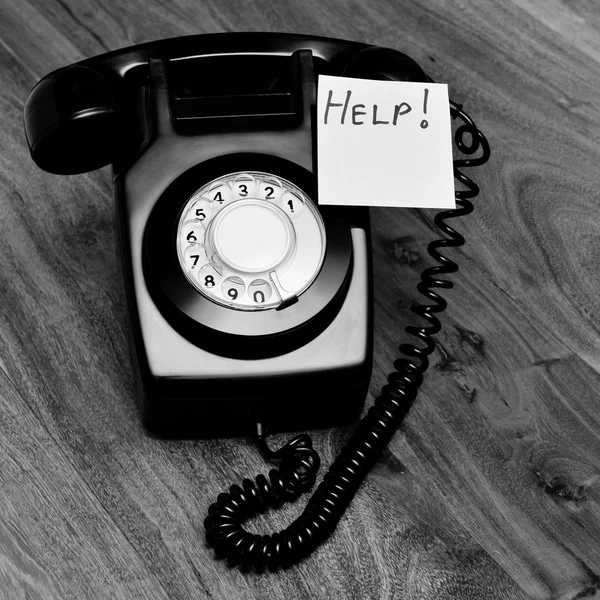 Telefone preto retro com uma nota de ajuda — Fotografia de Stock
