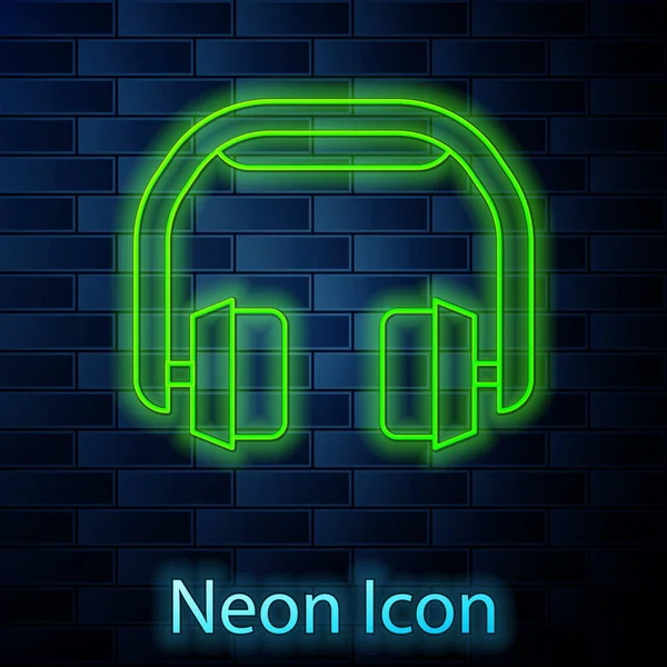 Linha de néon brilhante Headphones ícone isolado no fundo da parede de tijolo. Fones de ouvido. Conceito para ouvir música, serviço, comunicação e operador. Vetor — Vetor de Stock