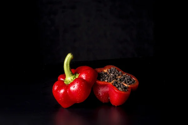 Pimentón rojo cortado en dos con pimienta negra seca en el interior —  Fotos de Stock