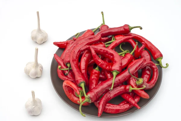 Chili auf Teller und Knoblauchköpfe isoliert — Stockfoto