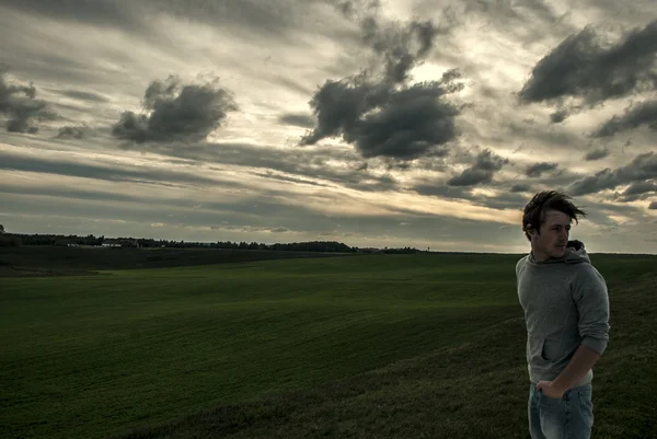 Junger Mann bleibt bei Wind auf dem Feld — Stockfoto