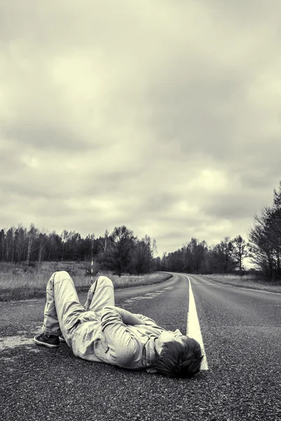 Young guy lies on the road — Stock Photo, Image
