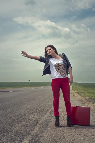 Fille debout sur la route avec valise cherche compagnon de voyage — Photo