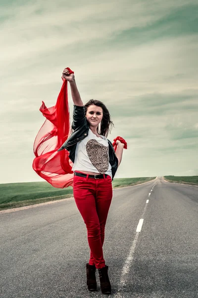 Menina bonita na estrada com abertura de tecido largo do vento — Fotografia de Stock
