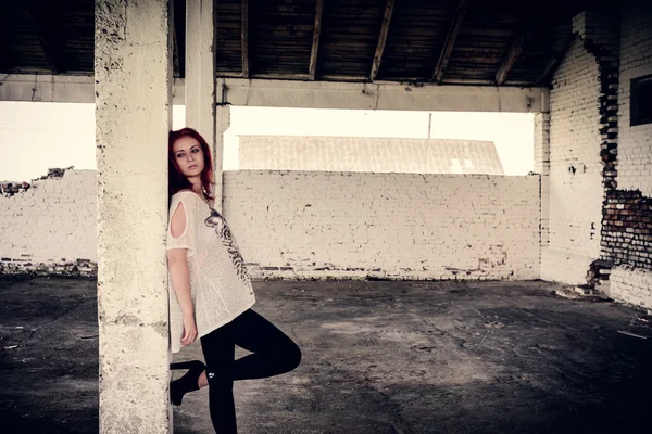 Beautiful girl with red hair outdoor in thrown old warehouse — Stock Photo, Image