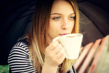 womanl şemsiyesi altında keyifle hoş kokulu kahve içer