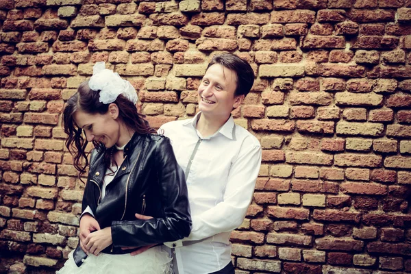 Unusual wedding couple near a brick wall — Stock Photo, Image