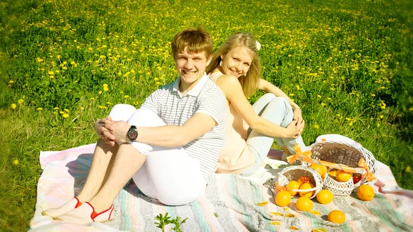 Gelukkige paar en picnic met sinaasappelen — Stockfoto