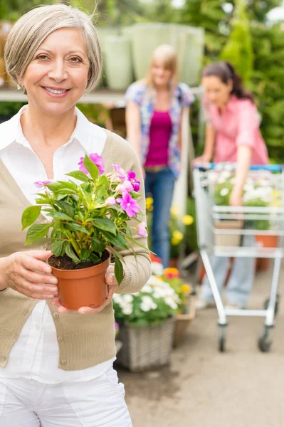 Mujer mayor mantenga maceta flor jardín tienda — Foto de Stock