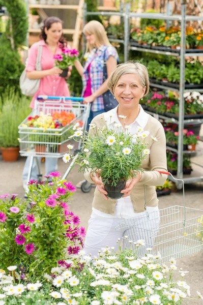 Gartencenter-Seniorin hält Topfblume in der Hand — Stockfoto